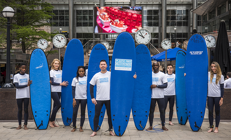 People standing in front of One Canada Square with surf boards