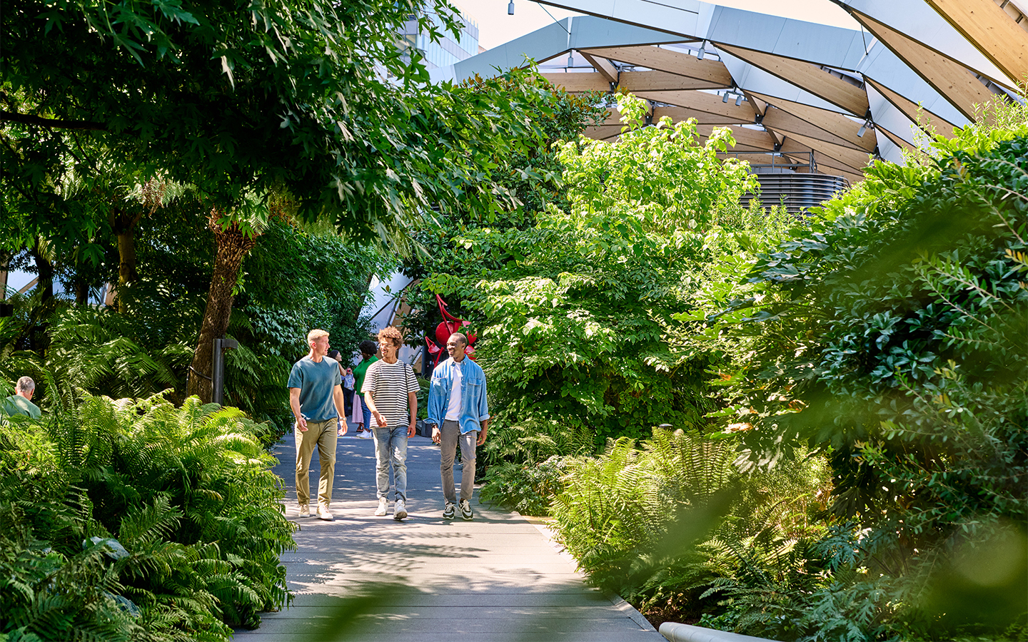 Three men walking through Crossrail Place Roof Garden